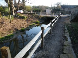 Cleft chestnut post and rail with twin galvanised wire below lower rail by mill leat