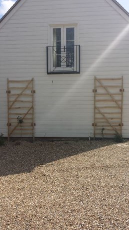 Chestnut panels attached to timber house for roses to climb up