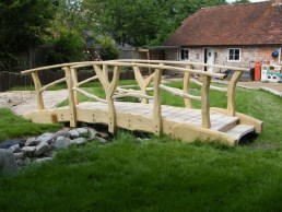 Green oak bridge over water feature