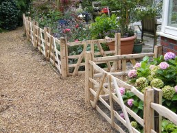 2 foot high sweet chestnut gate hurdles in front of flower border to keep dogs and chickens off