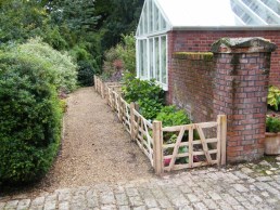 2 foot high sweet chestnut gate hurdles in front of flower border to keep dogs and chickens off 