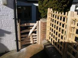 Chestnut trellis along top of brick wall with cottage gate
